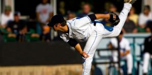 baseball pitcher in full extension on a baseball mound after throwing the ball