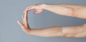 a pair of bare arms stretching the right wrist with the palm facing out