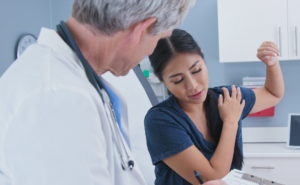 doctor examining patient with shoulder pain