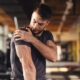 Handsome young man feeling the pain in shoulder at the gym