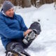 man holding hurt ankle in snow