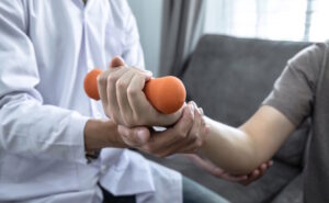 patient holding arm weight in physical therapy