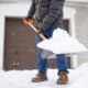 person with gloves on shoveling snow