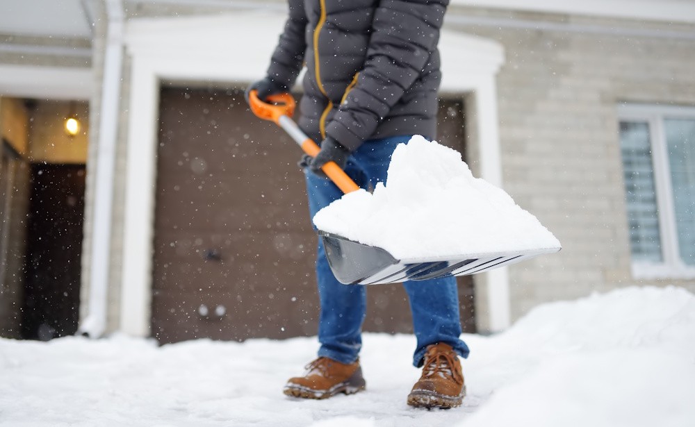 person with gloves on shoveling snow