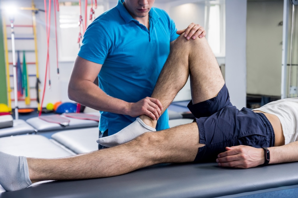 Rehabilitation therapy. Physiotherapist working with young male patient in the rehabilitation center.