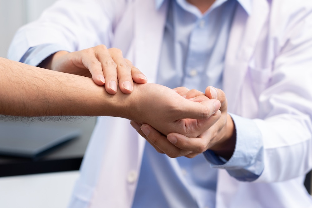 Medical concept a male doctor diagnosing a male patient’s wrist by pressing the wrist bone.